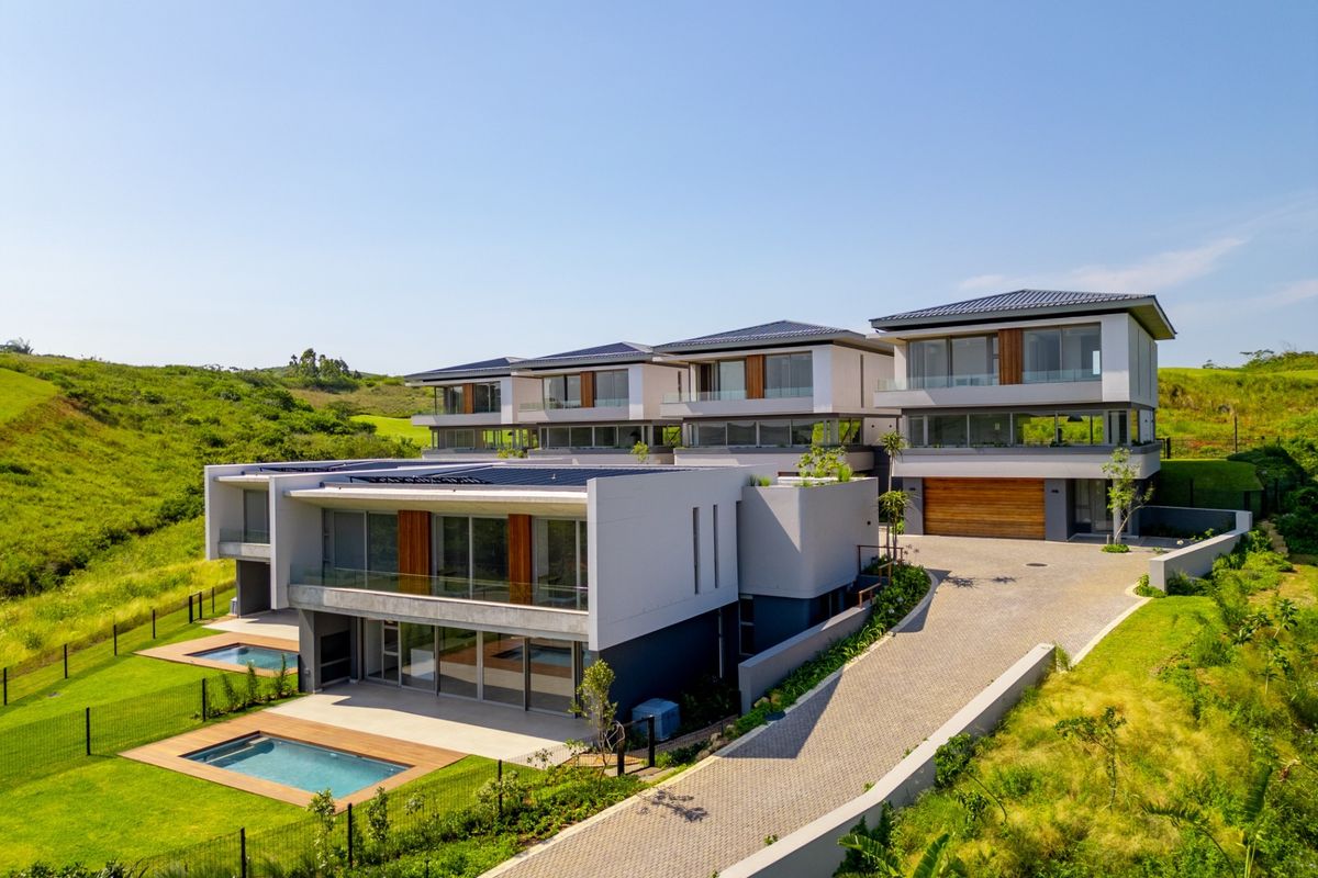 Aerial view of a modern multi-level residential complex featuring contemporary architecture, private swimming pools, paved driveways, and landscaped surroundings.