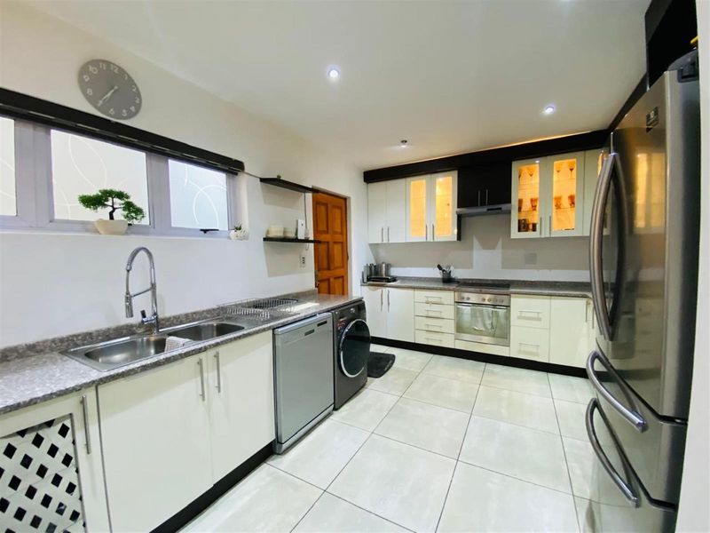 Modern kitchen featuring light-toned cabinetry, stone-look countertops, integrated oven and hob, and tiled flooring with recessed ceiling lighting.