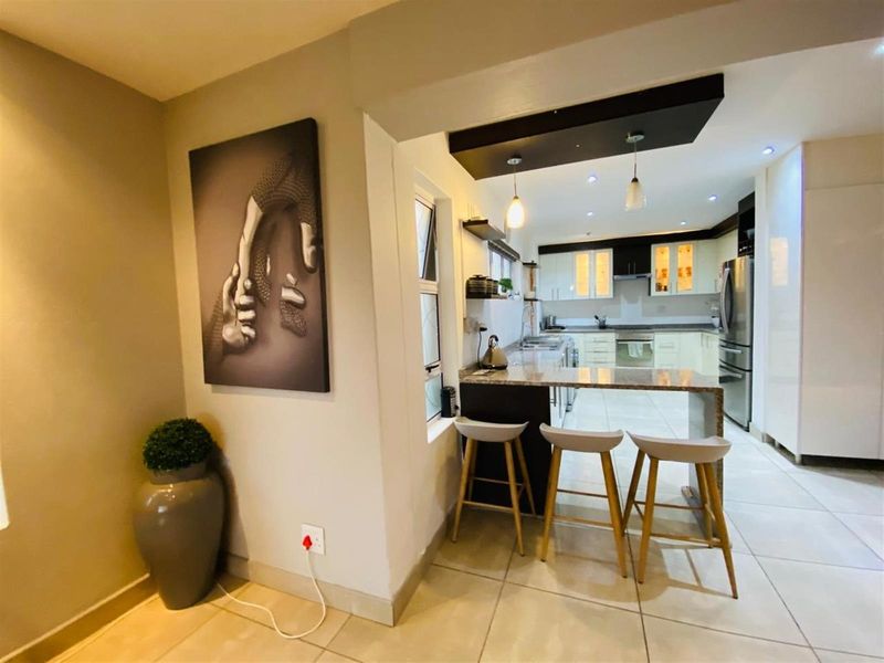 Modern open-plan kitchen featuring granite countertops, a breakfast bar, built-in cabinetry, and recessed lighting, seamlessly connecting to the adjacent living area.