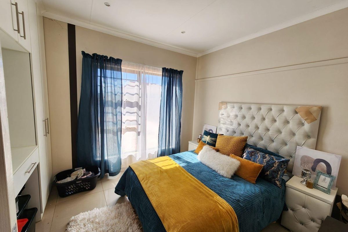 A bedroom featuring built-in cupboards, tiled flooring, and a window with natural light.