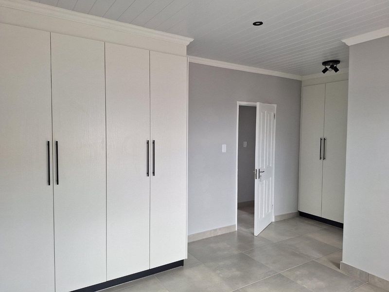 A modern bedroom featuring extensive built-in cabinetry, tiled flooring, and a tongue-and-groove ceiling with recessed lighting.