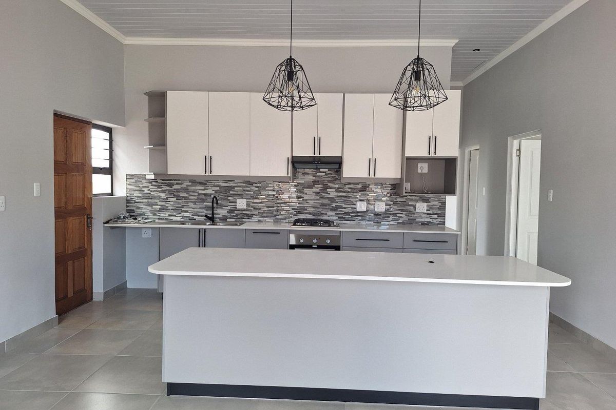 Modern kitchen featuring a central island, built-in cabinetry, mosaic tile backsplash, integrated oven and hob, and contemporary pendant lighting.