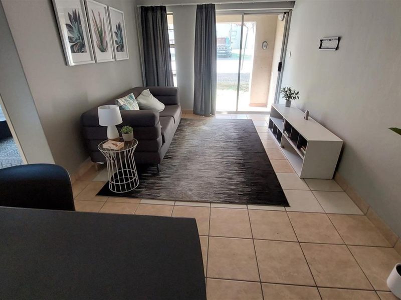 A living room area featuring tiled flooring and a sliding glass door providing access to the exterior.