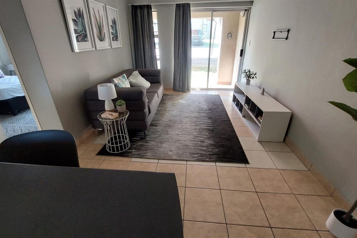 A living room area featuring tiled flooring and a sliding glass door providing access to the exterior.