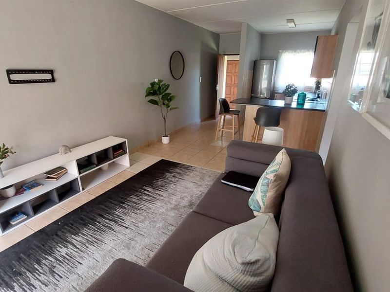 Open-plan living area featuring a kitchen with breakfast bar and tiled flooring, creating a functional and connected space.