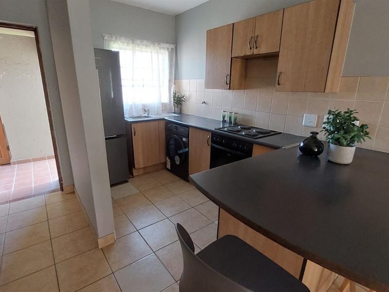 Functional kitchen featuring built-in cabinetry, laminate countertops, tiled backsplash, and a breakfast bar, offering a practical layout for daily meal preparation.
