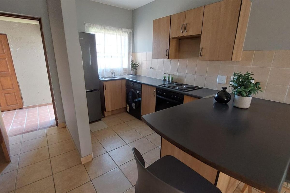 Functional kitchen featuring built-in cabinetry, laminate countertops, tiled backsplash, and a breakfast bar, offering a practical layout for daily meal preparation.