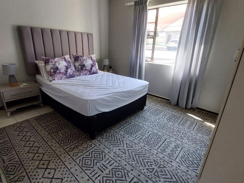 A well-maintained bedroom featuring neutral wall tones, tiled flooring, and a built-in wardrobe, offering a comfortable and functional living space.