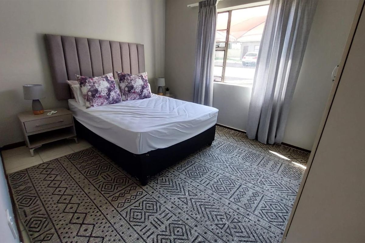A well-maintained bedroom featuring neutral wall tones, tiled flooring, and a built-in wardrobe, offering a comfortable and functional living space.