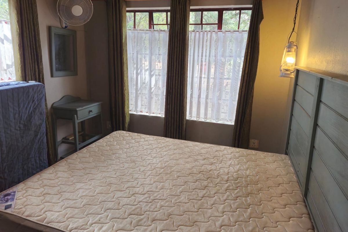 A bedroom featuring a wooden headboard, multi-pane windows, and a wall-mounted fan.