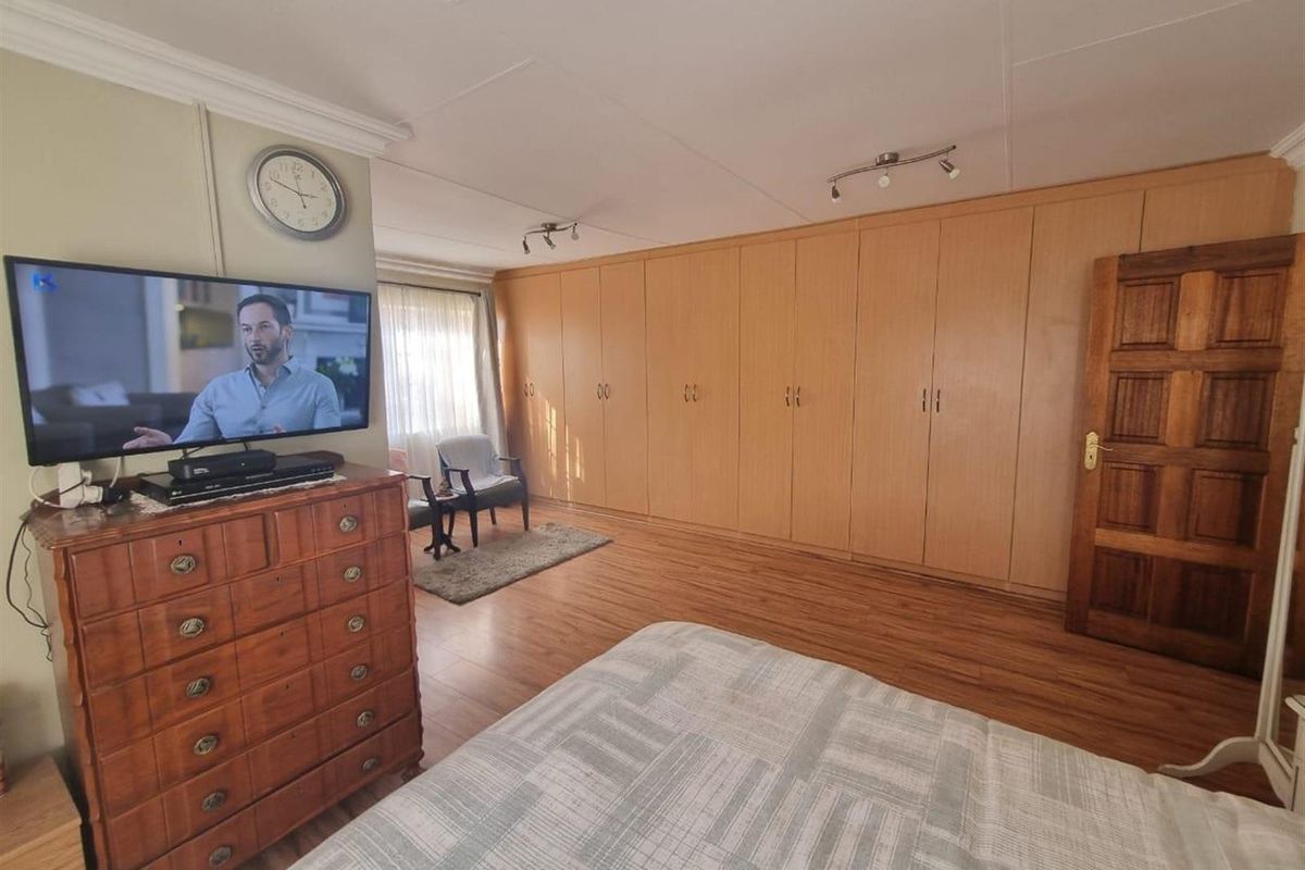 Spacious bedroom featuring extensive wall-to-wall built-in wooden cabinetry, laminate flooring, and crown molding detail.