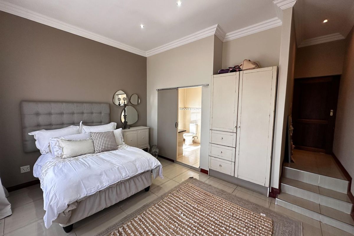 Spacious bedroom featuring tiled flooring, crown molding, recessed lighting, and an en-suite bathroom accessed via a sliding door.