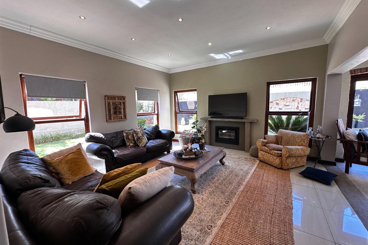 Spacious living room featuring a built-in fireplace, tiled flooring, recessed ceiling lighting, and large windows providing natural light and garden views.