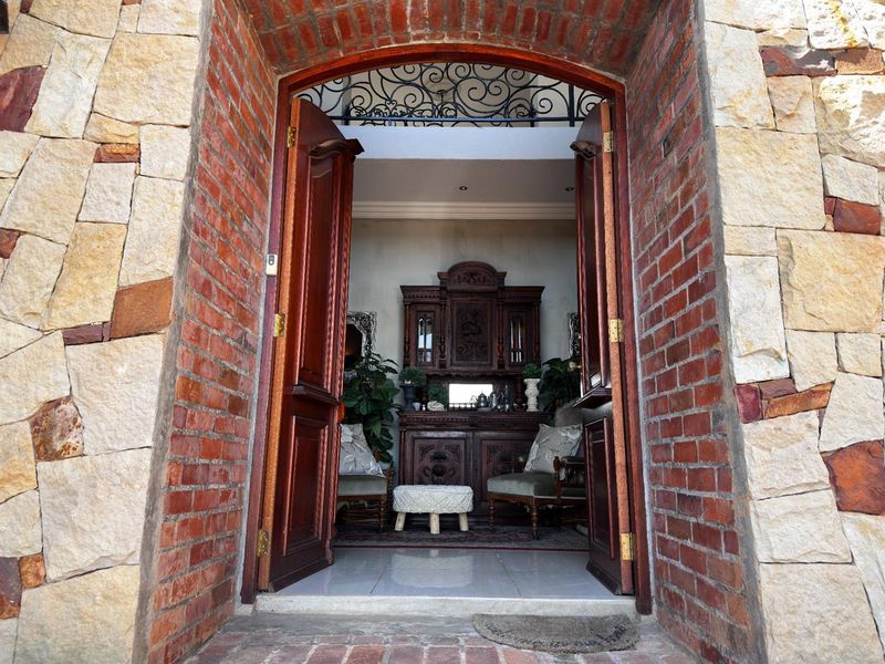 A welcoming entrance featuring a classic arched doorway with exposed brick and stone cladding, leading into a foyer with tiled flooring.
