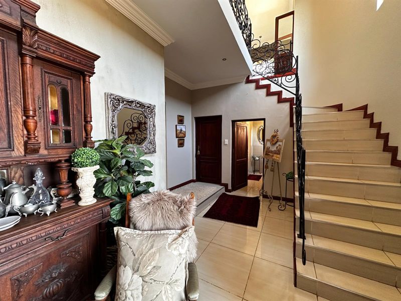 Spacious entrance hall featuring a grand staircase with decorative wrought iron balustrades and polished tile flooring.