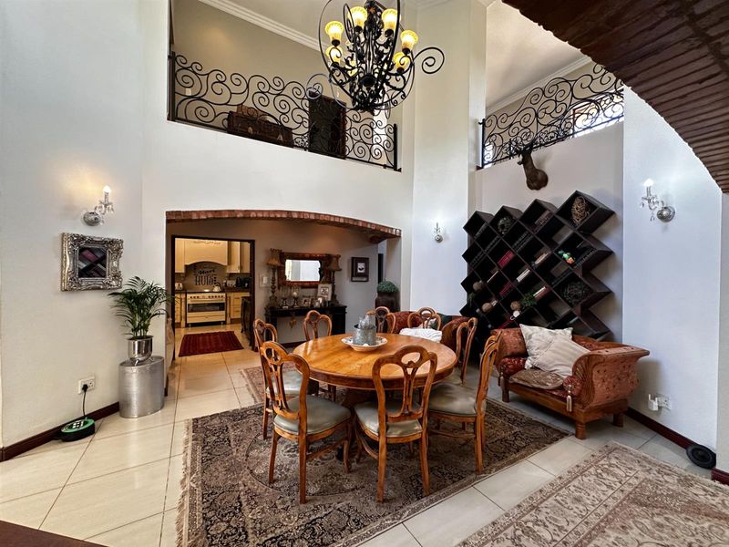 Spacious open-plan dining area featuring double-volume ceilings, decorative wrought iron balustrades, and a brick archway leading to the kitchen.