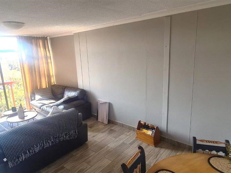 A spacious living area featuring tiled flooring and a large sliding glass door that provides access to the balcony and natural light.
