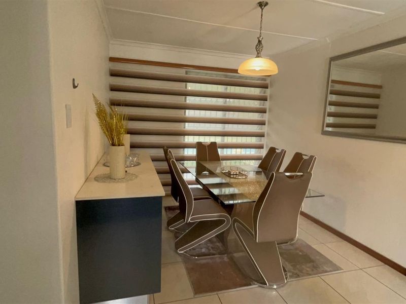 A dining room featuring tiled flooring, a built-in sideboard, and a window fitted with modern zebra-style blinds.