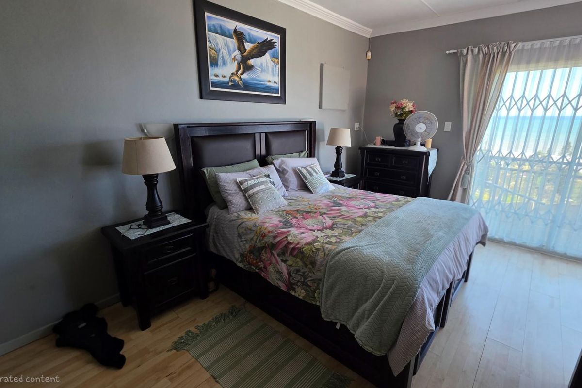 A well-lit bedroom featuring light wood-look flooring, neutral wall tones, and a sliding glass door with security gate providing access to an outdoor view.