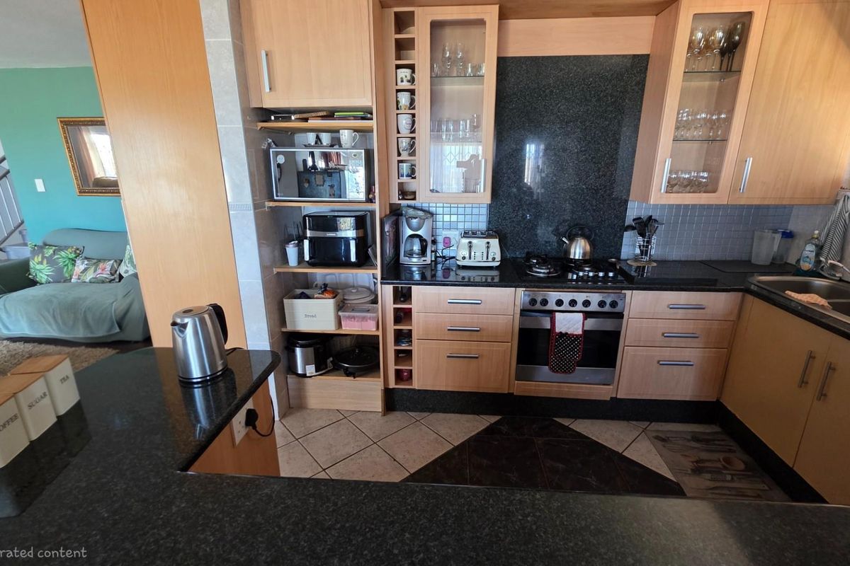 A functional kitchen featuring light wood cabinetry, dark granite countertops, a built-in oven, gas hob, and an integrated extractor fan.