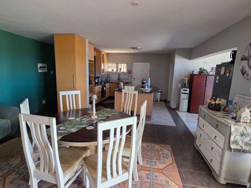 Open-plan living and dining area featuring a functional kitchen with built-in cabinetry and tiled flooring throughout.