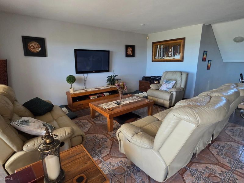 A comfortable living room featuring tiled flooring and an integrated staircase leading to the upper level.
