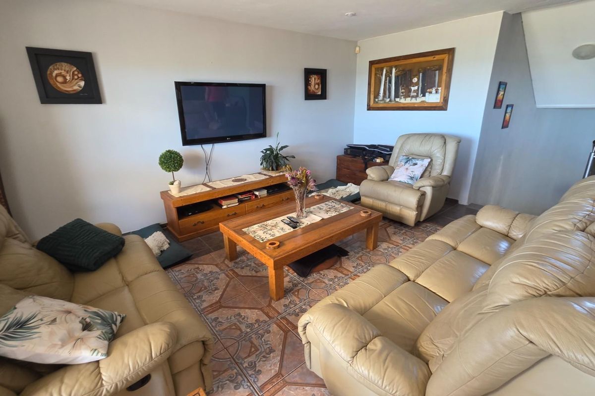 A comfortable living room featuring tiled flooring and a wall-mounted television setup.