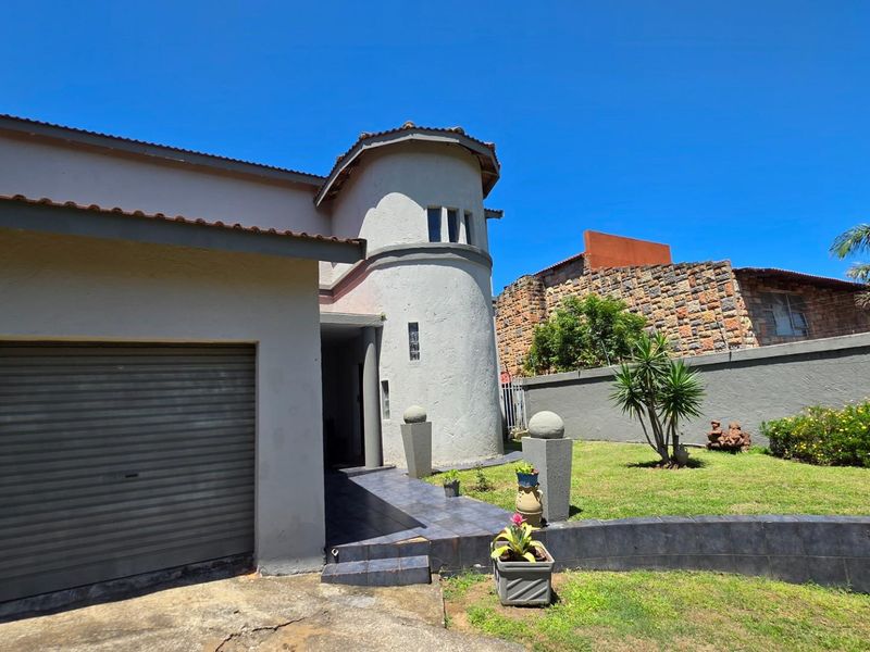 Front exterior view of the property featuring a distinctive turret-style architectural element, a single garage, and a landscaped front garden area.