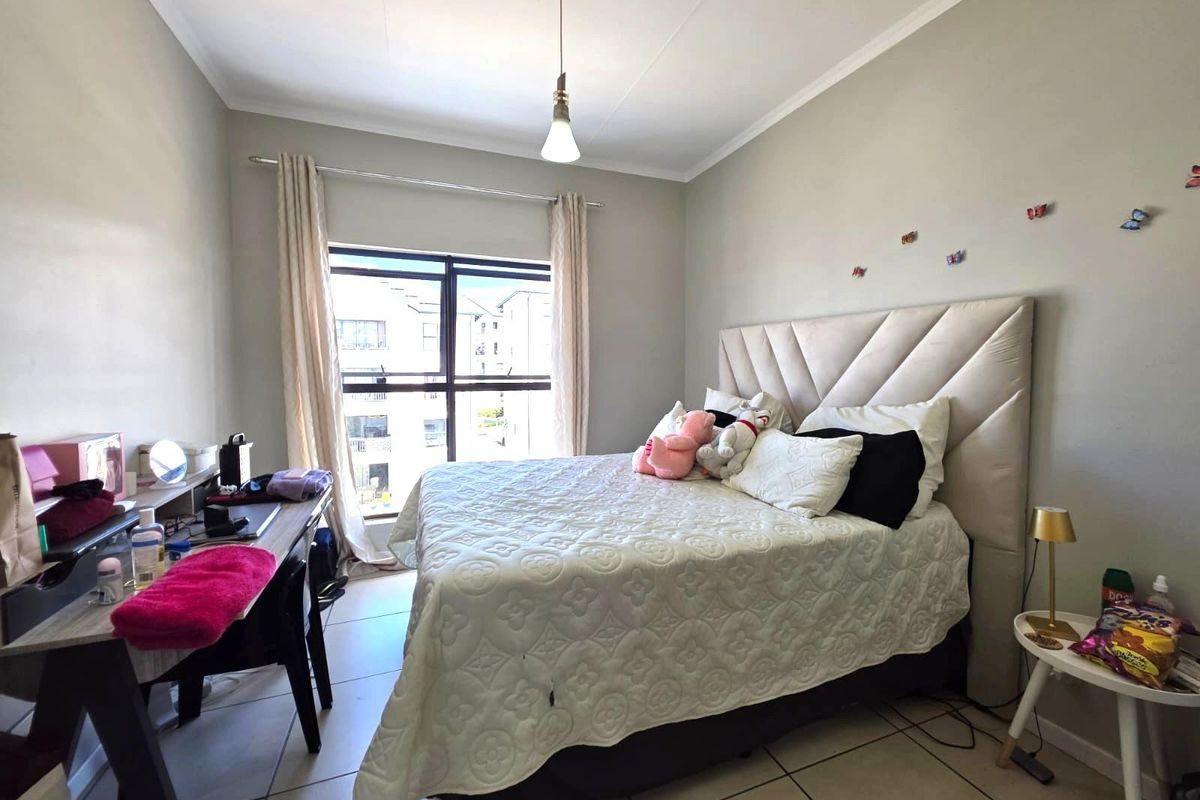 A well-lit bedroom featuring tiled flooring, a large window providing natural light, and a neutral color palette.