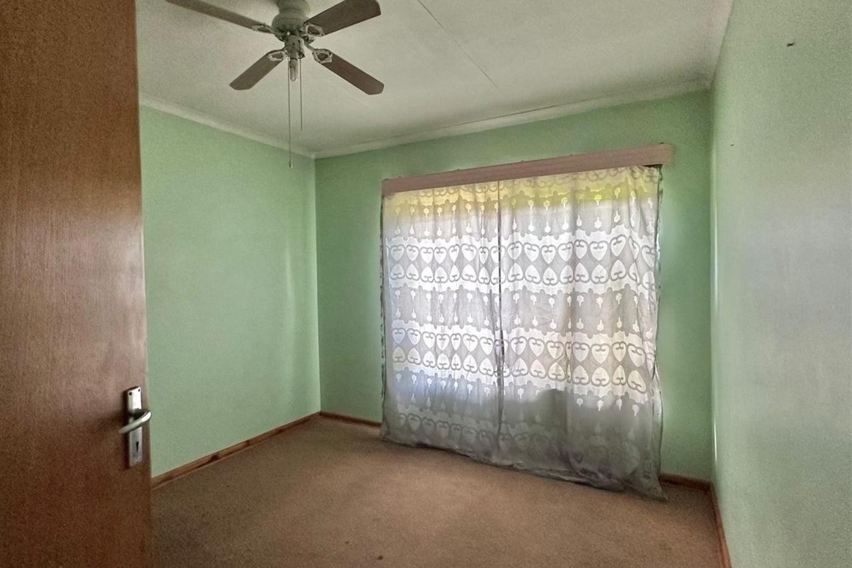 A simple bedroom featuring a ceiling fan and carpeted flooring, offering a blank canvas for potential updates and personalization.