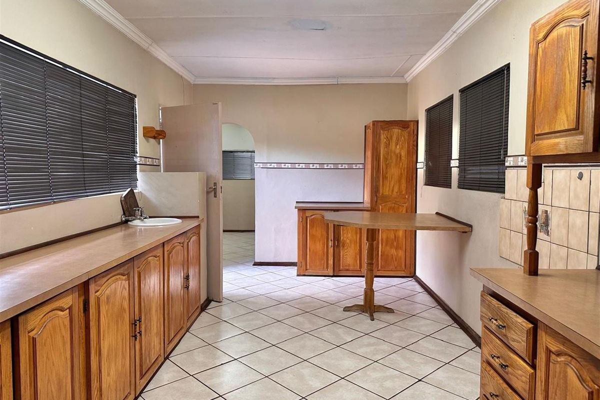 A functional kitchen featuring wooden cabinetry, tiled flooring, and a built-in breakfast nook, offering a practical layout with potential for modern updates.