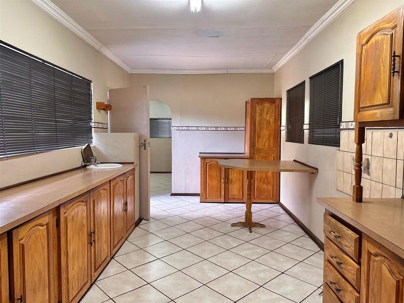A functional kitchen featuring wooden cabinetry, tiled flooring, and a built-in breakfast nook, offering a practical layout with potential for modern updates.