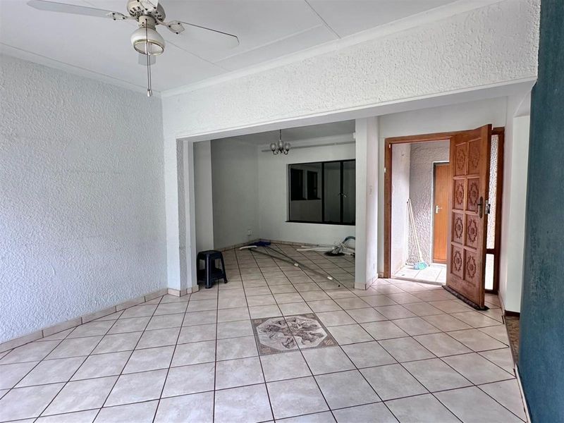 An open-plan living area featuring tiled flooring, a ceiling fan, and direct access to an exterior entrance.