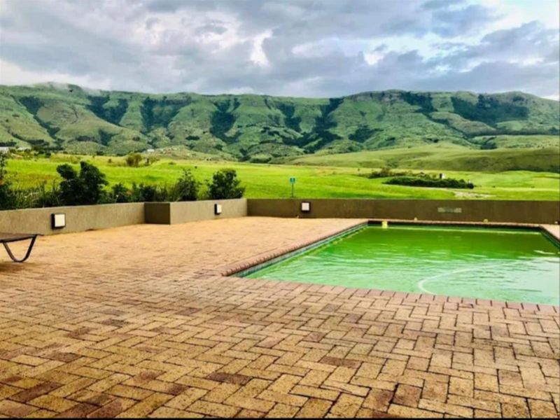 Outdoor pool area featuring a paved deck, retaining wall with integrated lighting, and scenic mountain views.