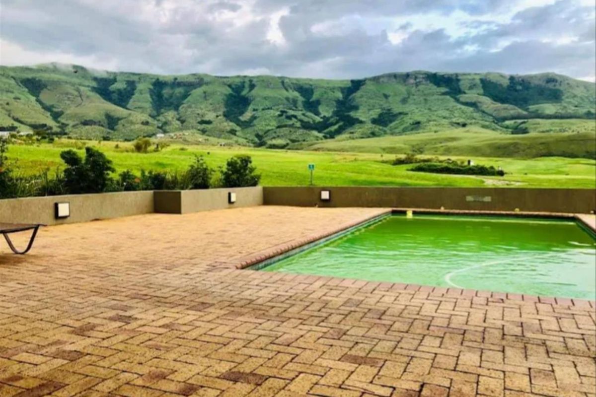 Outdoor pool area featuring a paved deck, retaining wall with integrated lighting, and scenic mountain views.