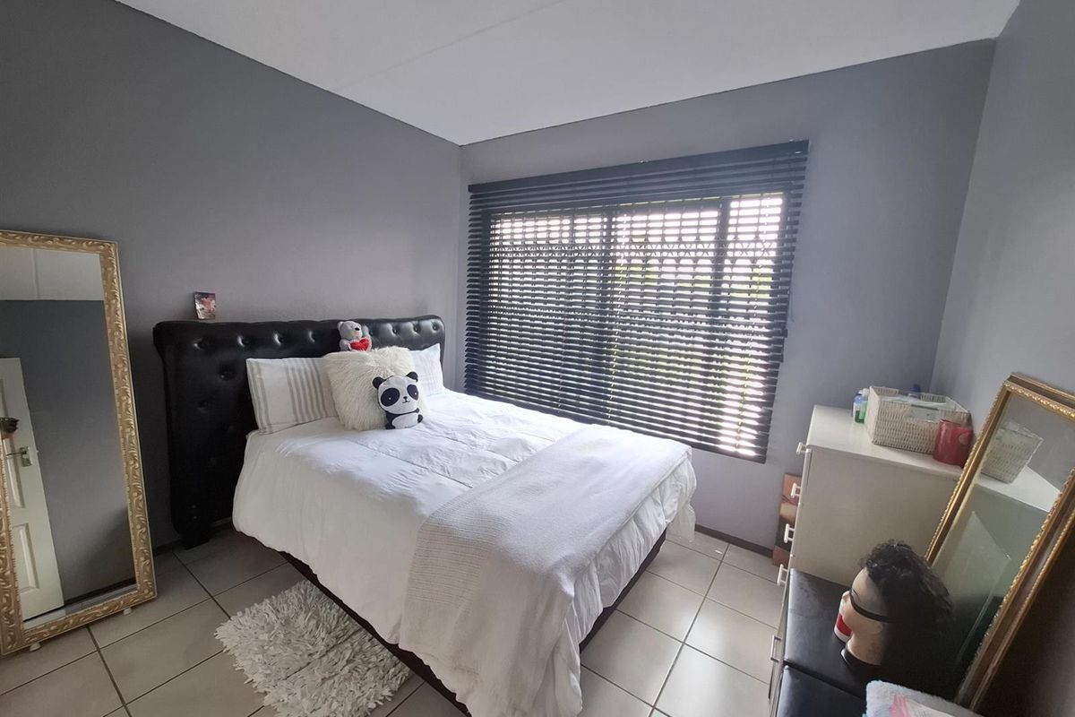 A bedroom featuring tiled flooring, grey painted walls, and dark horizontal window blinds.