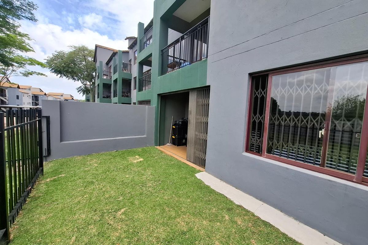 Ground floor apartment exterior featuring a private lawn area, security gates on windows and doors, and access to a covered patio space.