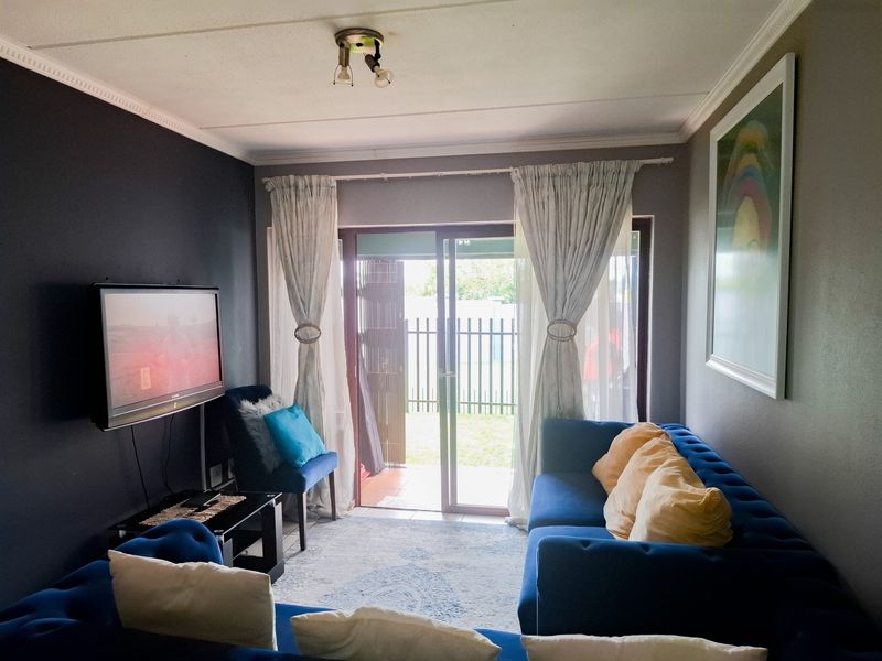 A living room featuring a sliding glass door providing access to an outdoor area, finished with ceiling cornicing and neutral wall tones.