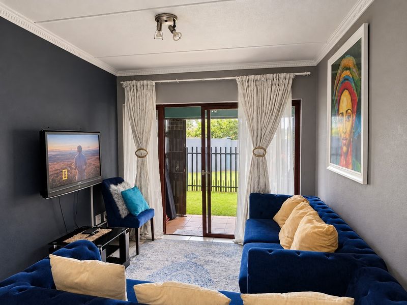 A well-maintained living room featuring dark accent walls, ceiling cornicing, and a sliding glass door providing direct access to the outdoor patio area.