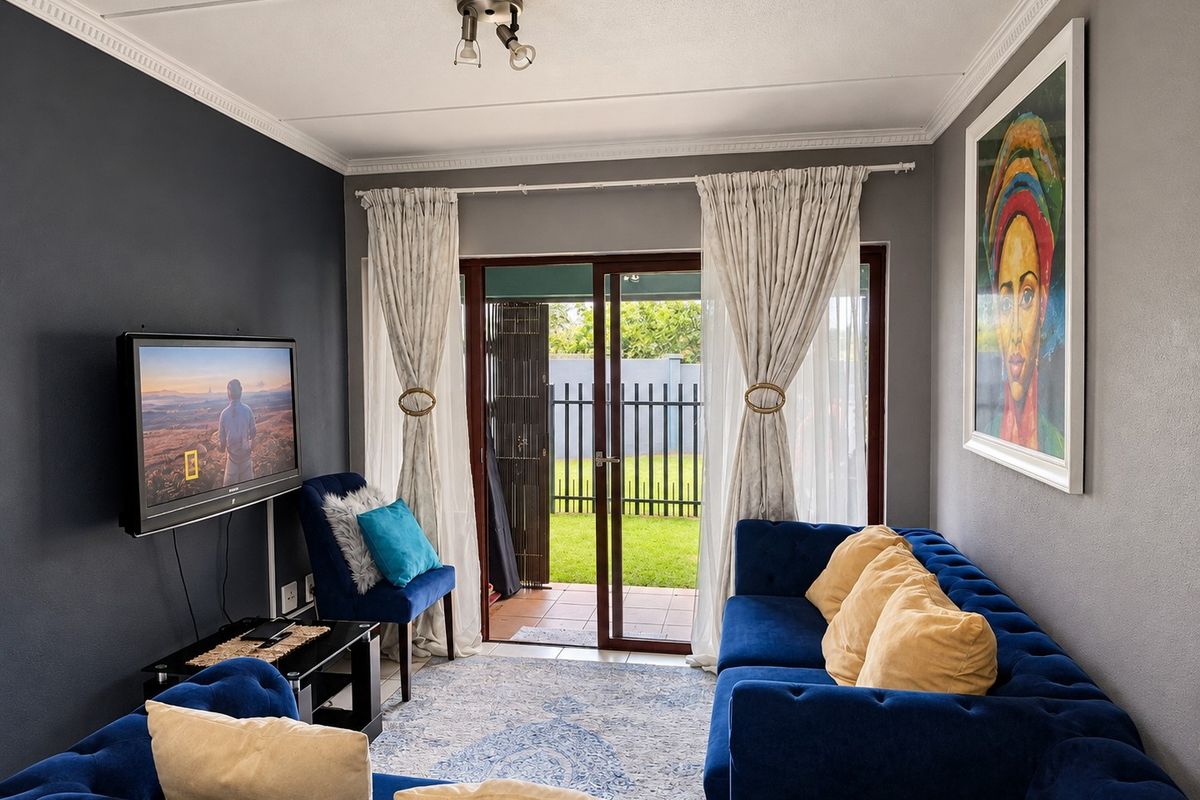 A well-maintained living room featuring dark accent walls, ceiling cornicing, and a sliding glass door providing direct access to the outdoor patio area.