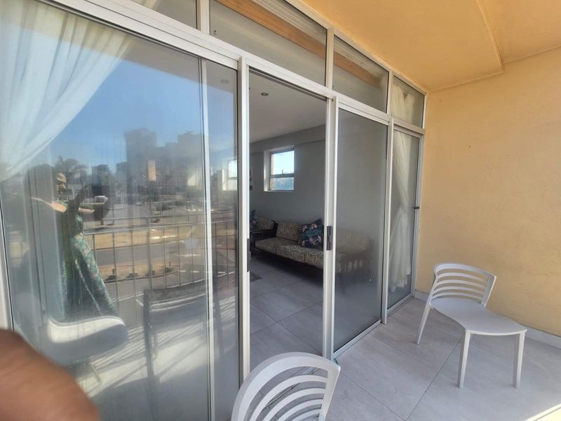 A covered balcony featuring tiled flooring and large sliding glass doors providing access to the interior living area.
