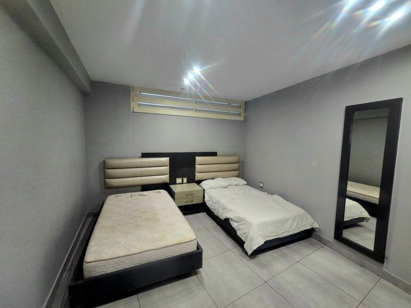 A bedroom featuring tiled flooring, recessed ceiling lights, and a built-in headboard design.