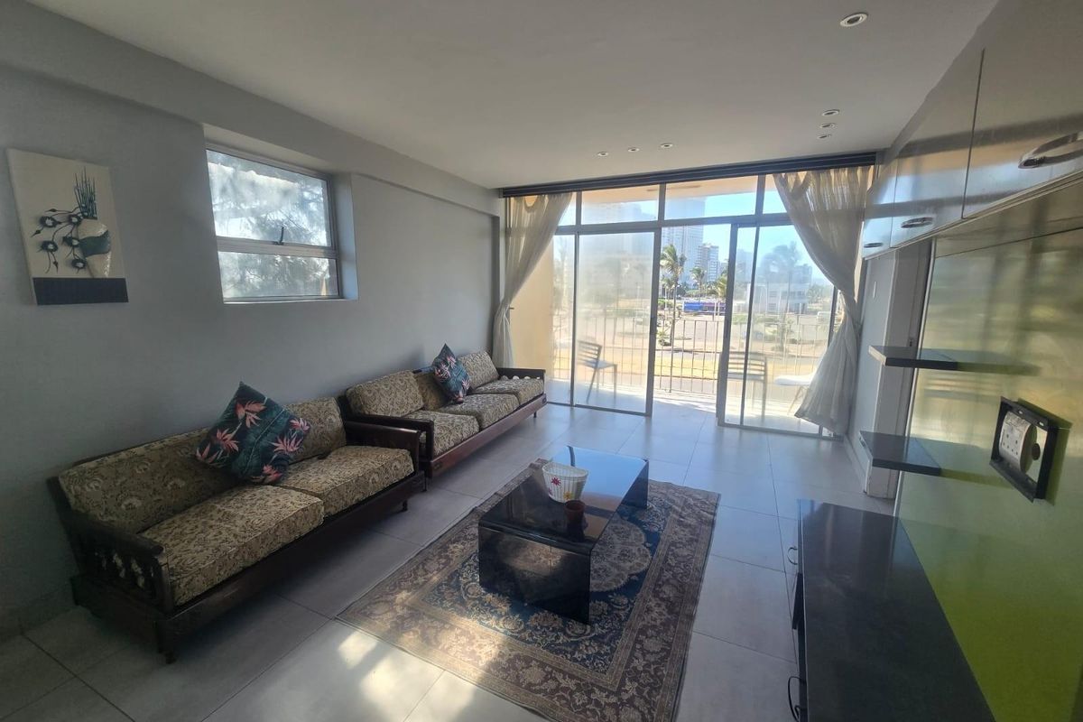 A bright living room featuring large sliding glass doors leading to a balcony, tiled flooring, and built-in wall cabinetry with recessed lighting.