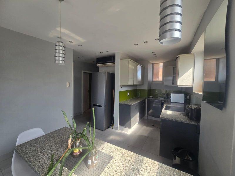 Modern kitchen featuring granite countertops, ample built-in cabinetry, recessed lighting, and tiled flooring, creating a functional and contemporary culinary space.