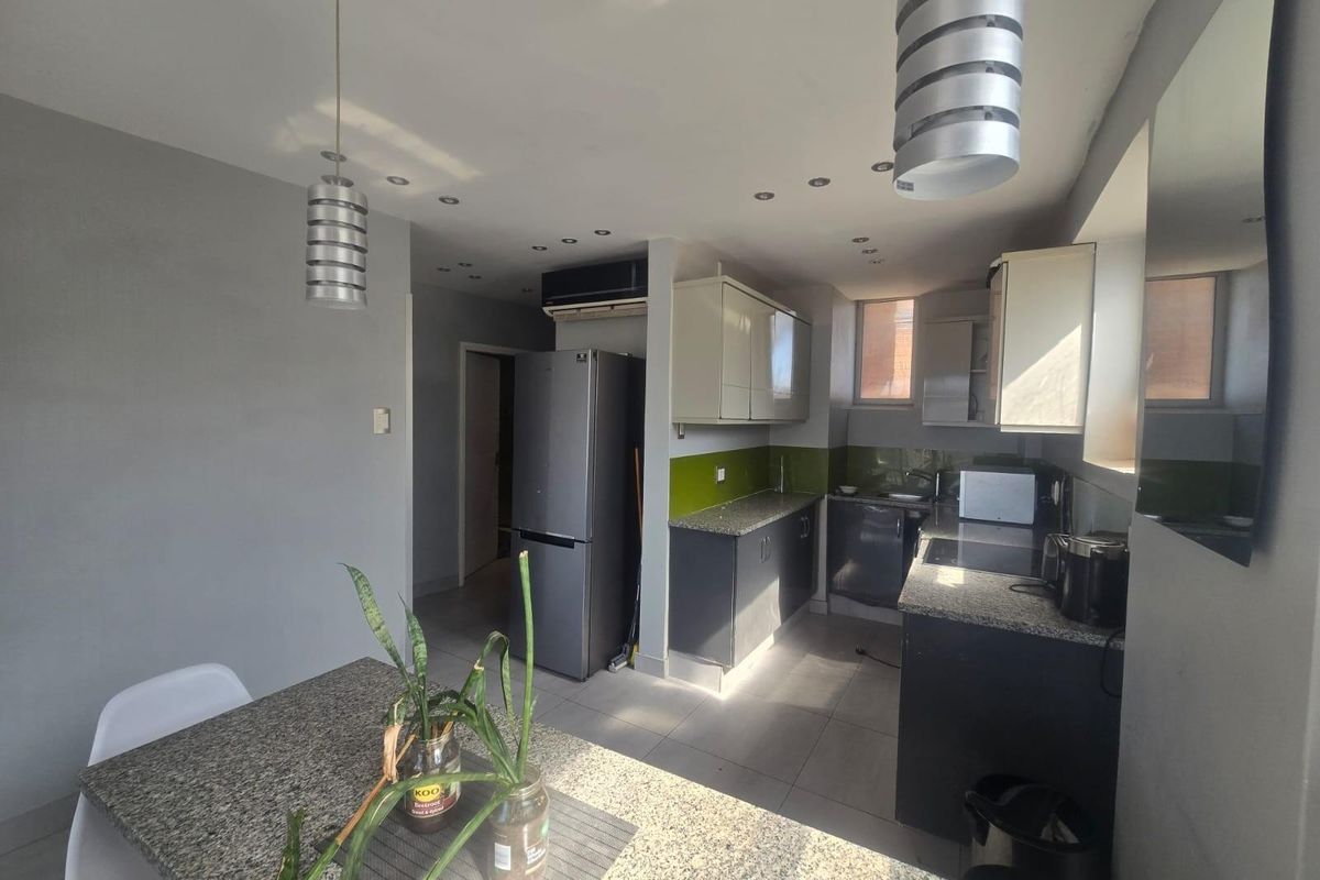 Modern kitchen featuring granite countertops, ample built-in cabinetry, recessed lighting, and tiled flooring, creating a functional and contemporary culinary space.
