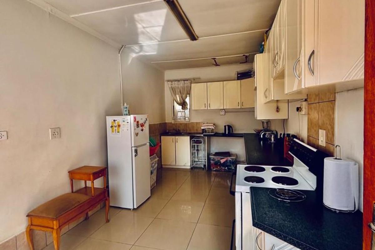 A functional kitchen featuring white cabinetry, dark countertops, tiled flooring, and a built-in stove, offering a practical layout for daily meal preparation.