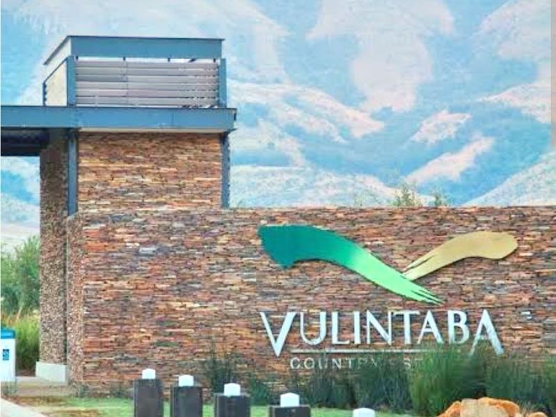 The entrance gatehouse of Vulintaba Country Estate, featuring stone cladding, professional signage, and a well-maintained landscaped approach with mountain views.
