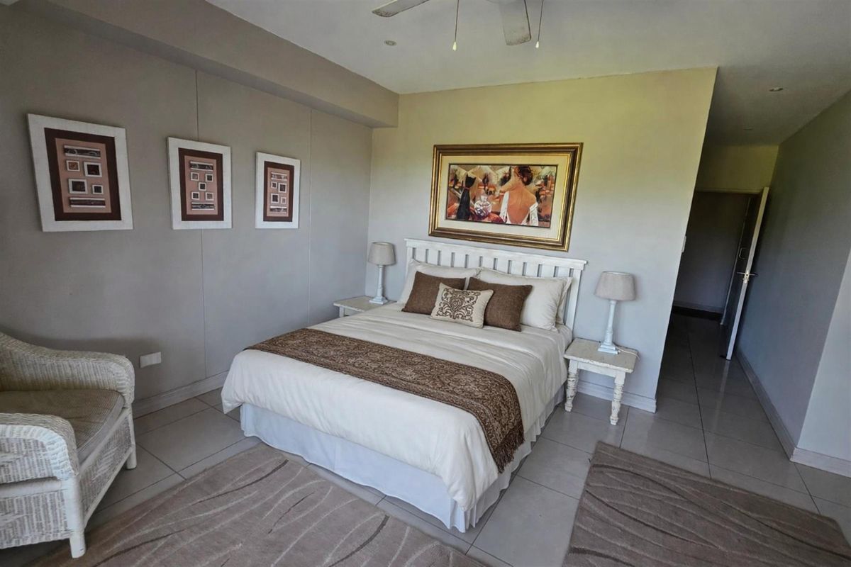 A well-lit bedroom featuring tiled flooring, a ceiling fan, and neutral wall finishes, providing a comfortable and functional living space.