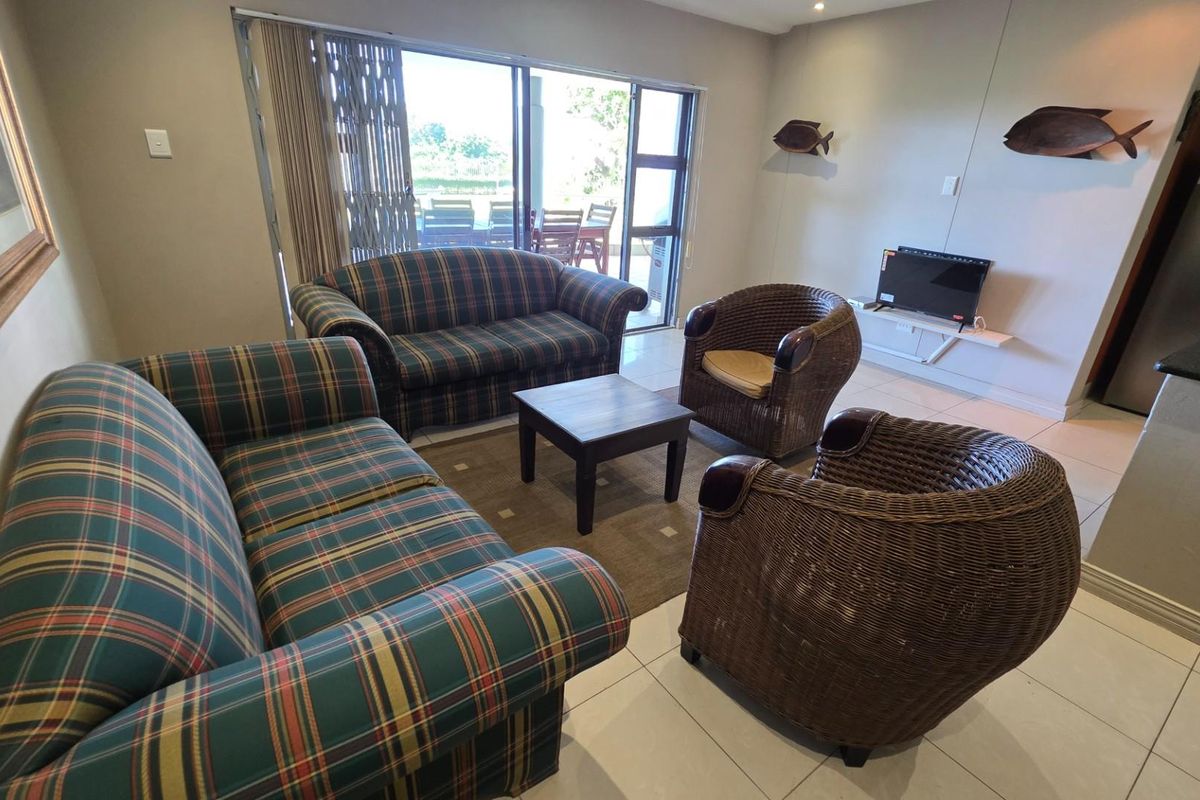 A comfortable living area featuring tiled flooring and large sliding glass doors that provide access to an outdoor patio space.
