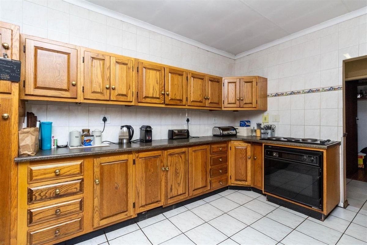 A functional kitchen featuring traditional oak-style cabinetry, tiled walls, and a built-in oven with a hob.